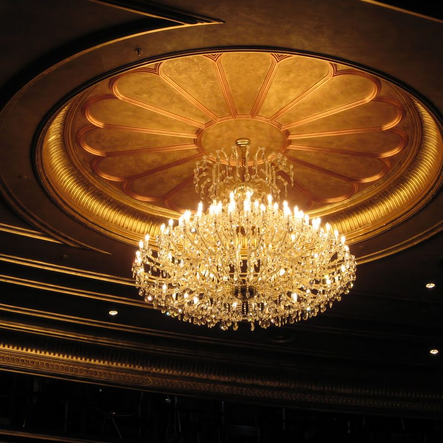 Crystal chandelier beneath a domed and gilded hotel ceiling