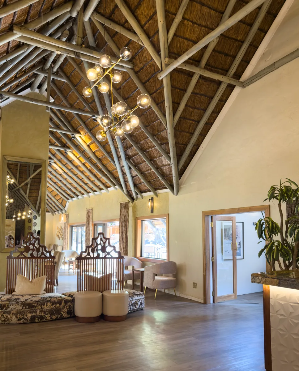Cascading brass orb chandelier suspended beneath a soaring thatched lodge roof